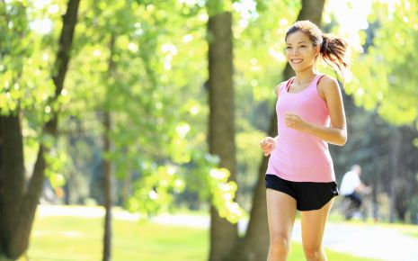Das Bild zeigt eine junge Frau, die im Wald joggt.