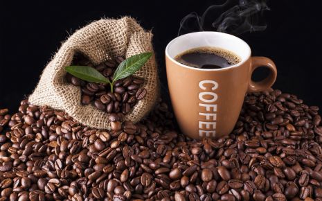 Man sieht Kaffeebohnen und eine Tasse Kaffee.