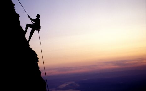 Das Bild zeigt einen Mann, der einen Berg hochklettert.