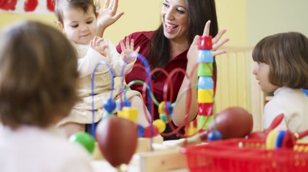 Das Bild zeigt eine Frau, die mit Kindern spielt.
