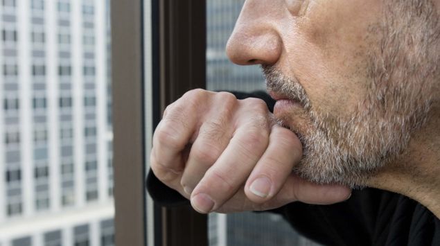 Ein Mann schaut nachdenklich aus dem Fenster eines Hochhauses