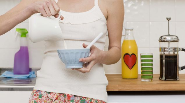 Das Bild zeigt eine Frau, die Milch in eine Schüssel giesst.