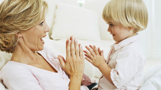 Das Bild zeigt eine Frau, die mit einem kleinen Jungen spielt.