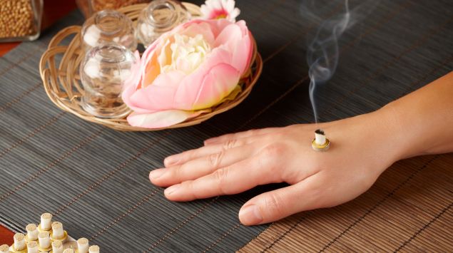 Moxa-Therapie auf einer Hand.