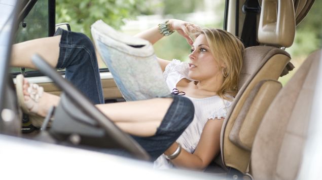 Man sieht eine Frau im Auto, die eine Karte in der Hand hält.