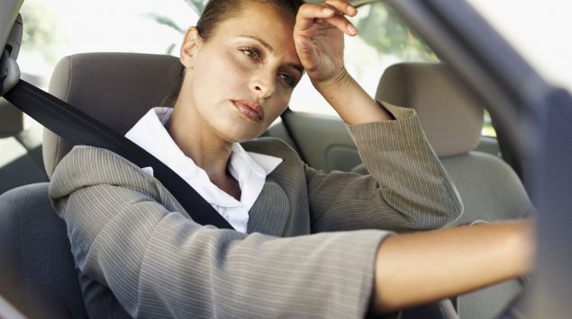 Das Bild zeigt eine Frau am Steuer eines Autos sitzend.
