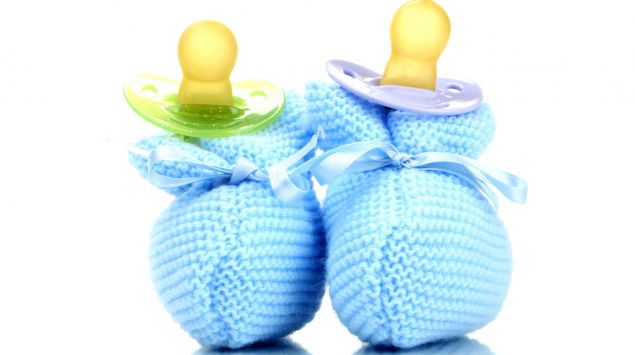 Das Bild zeigt ein Paar blaue Babyschuhe und zwei Schnuller.