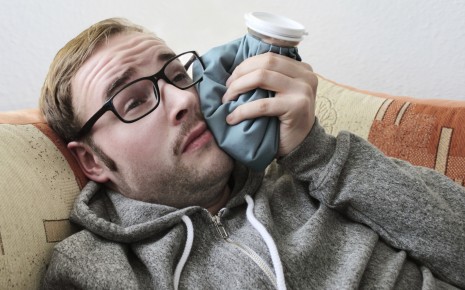 Ein Mann mit Zahnschmerzen kühlt seine Wange mit einem Eisbeutel.