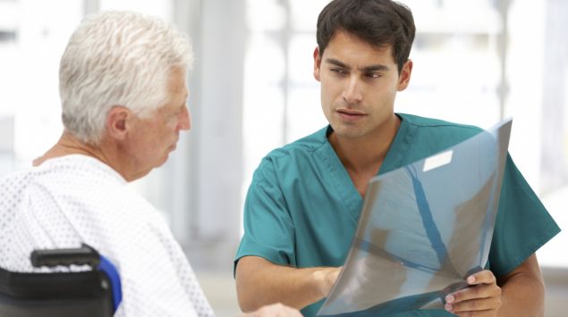 Ein Arzt zeigt einem älteren Patienten ein Röntgenbild.