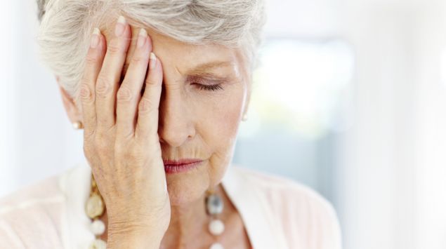 Eine Frau bedeckt die rechte Gesichtshälfte mit ihrer Hand.