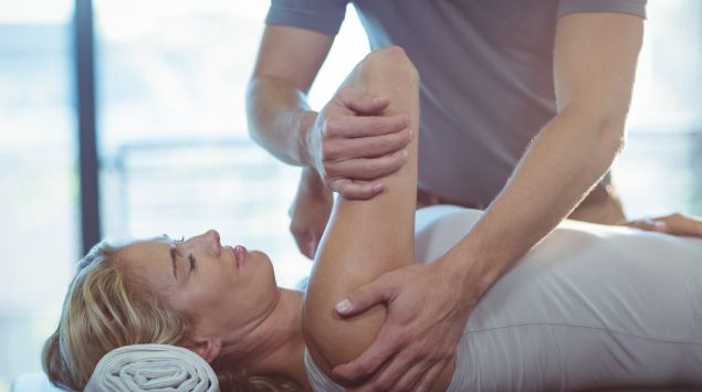 Ein Physiotherapeut behandelt die Schulter einer Patientin.