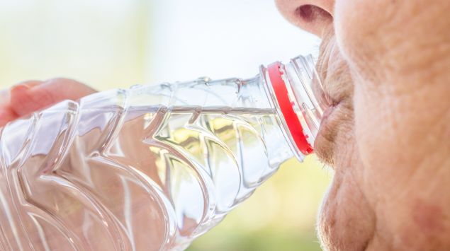 Eine ältere Frau trinkt Wasser.
