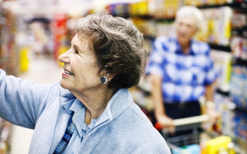 Vitamin D: Eine ältere Frau greift im Supermarkt nach einer Ware im Regal.