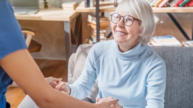 Eine Physiotherapeutin hilft einer Seniorin beim Aufstehen.