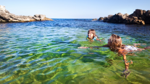 Mutter und Tochter schwimmen in Meeresbucht.