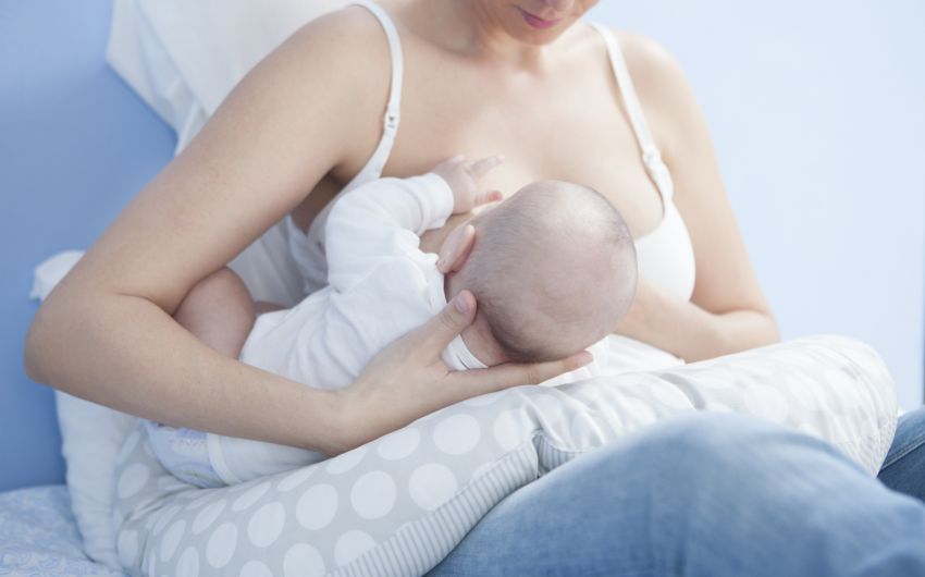 Eine Mutter stillt ihr Baby in der Rückenhaltung
