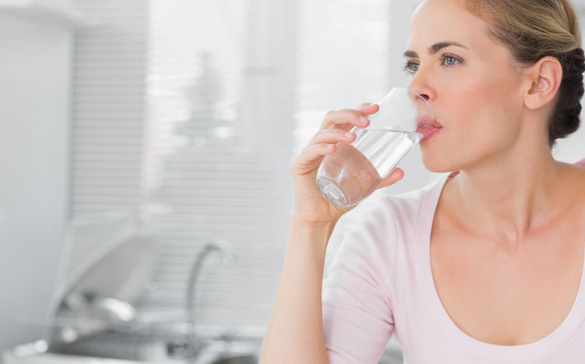 Eine Frau trinkt ein Glas Wasser.