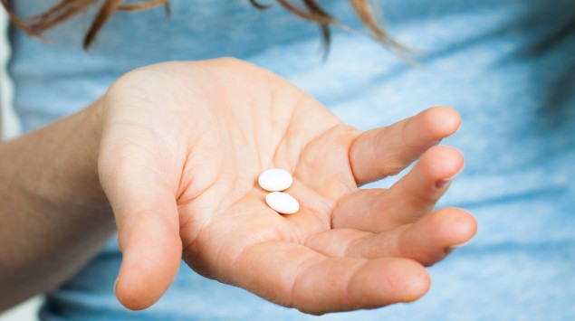 Jemand hält Tabletten in der rechten Hand und fragt sich: Vertragen sich Antibiotika und Milch?