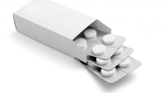 Man sieht eine weiße Pappschachtel mit weißen Tabletten.