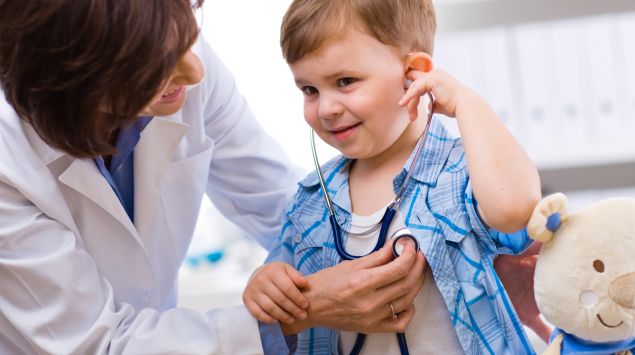 Eine Kinderärztin hört einen kleinen Jungen ab.