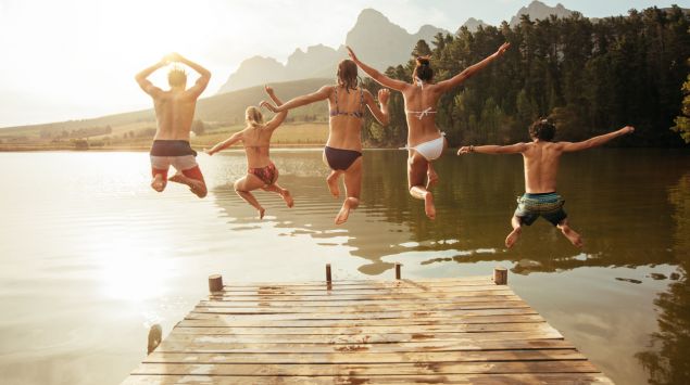 Freunde springen gemeinsam in einen See.
