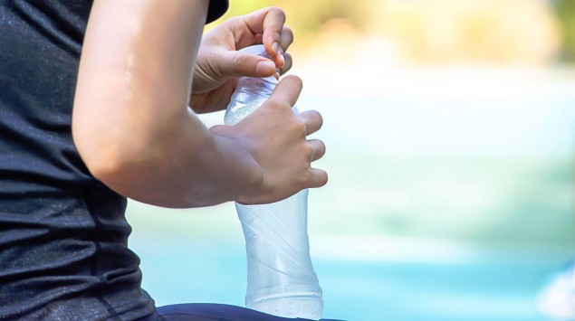 Eine Frau hält eine leere Wasserflasche in den Händen.