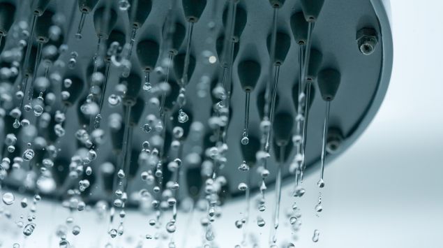 Man sieht einen Duschkopf, aus dem Wasser perlt.